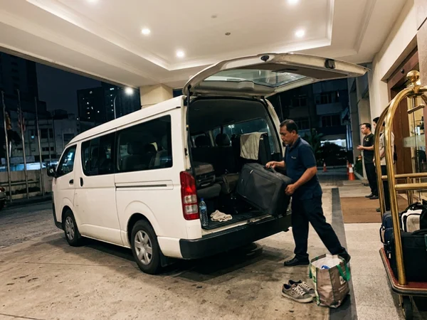 A private air-conditioned van at a Kuala Lumpur hotel entrance at dawn